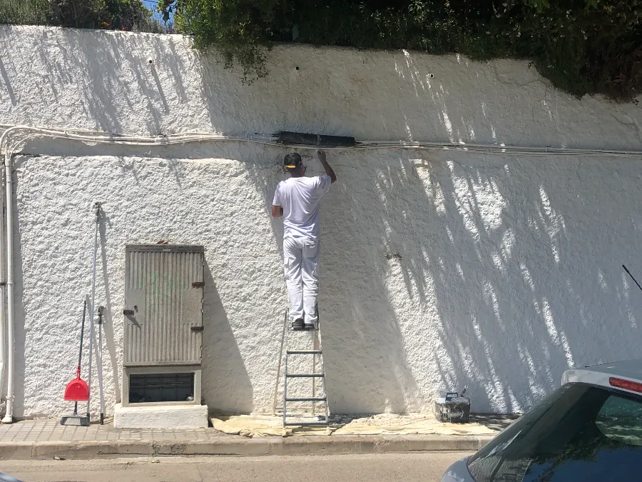 Una persona pinta una pared alta subida a una escalera